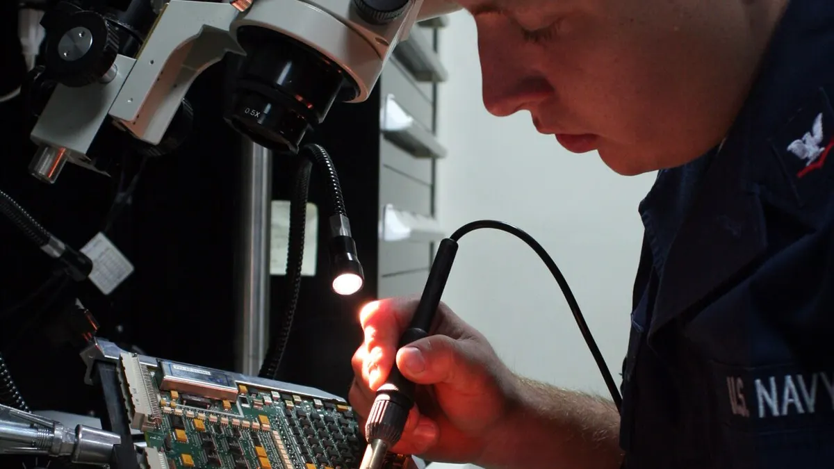 An electronics repair technician working at a professional bench